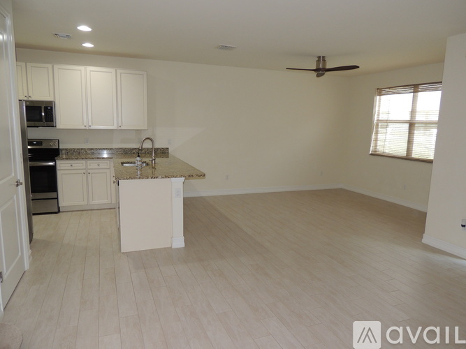 A spacious kitchen with white cabinets and a marble island.