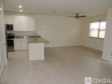 A spacious kitchen with white cabinets and a marble island.