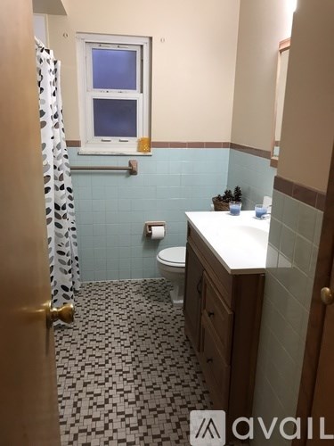 A bathroom with a toilet, sink, and a window.