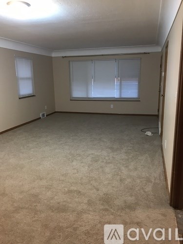 A room with beige carpet and a window with blinds.