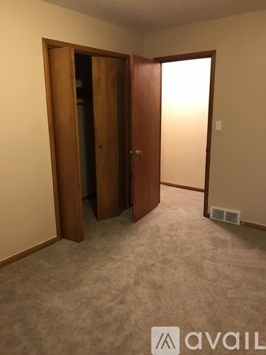 A room with a carpeted floor and a wooden door.