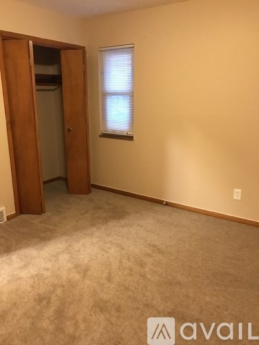A room with a carpeted floor and a window with blinds.