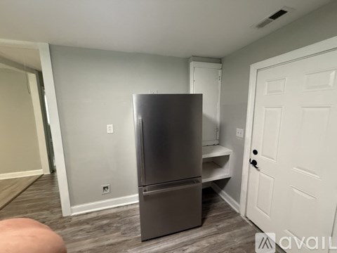 A kitchen with a stainless steel refrigerator and a white door.