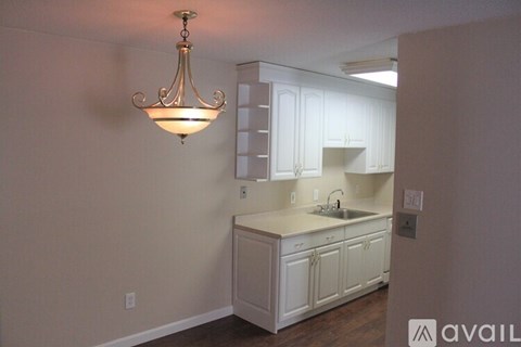 A kitchen with white cabinets and a chandelier hanging from the ceiling.