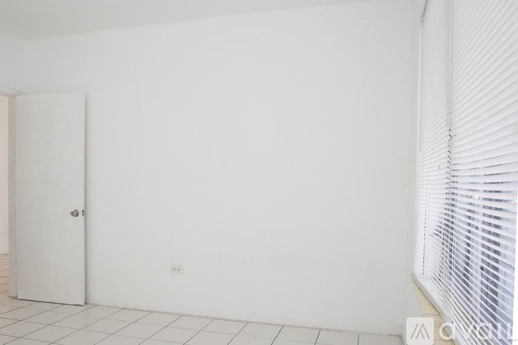 A white door is on the left and a window with blinds is on the right.