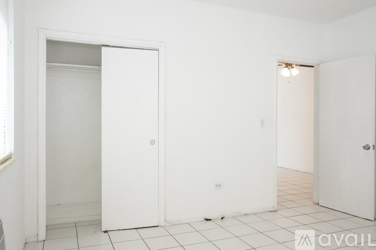 A white door is open in a room with white walls and tiled flooring.