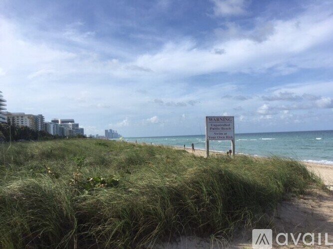 A beach scene with a warning sign in the foreground.