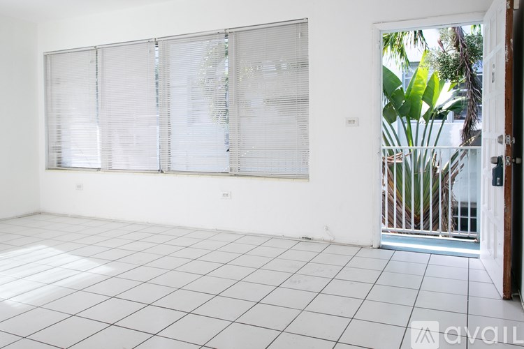 A room with white tiled flooring and a glass door leading to a balcony.