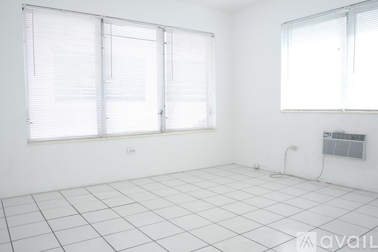 A room with white tiled floors and two windows with blinds.