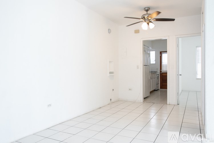 A room with a ceiling fan and a doorway leading to a kitchen.