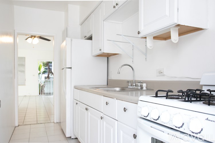 A white kitchen with a stove and sink.