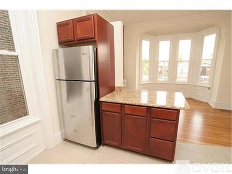 A kitchen with a refrigerator and wooden cabinets.