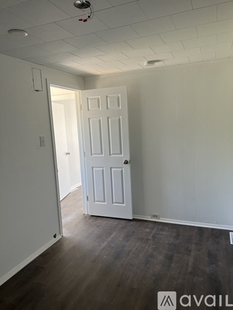 A room with a white door and wooden floor.