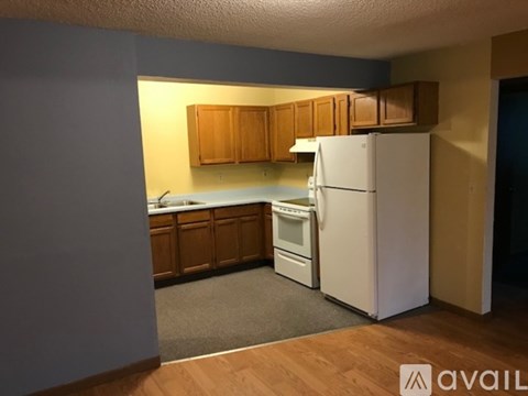 A kitchen with a white refrigerator and wooden cabinets.