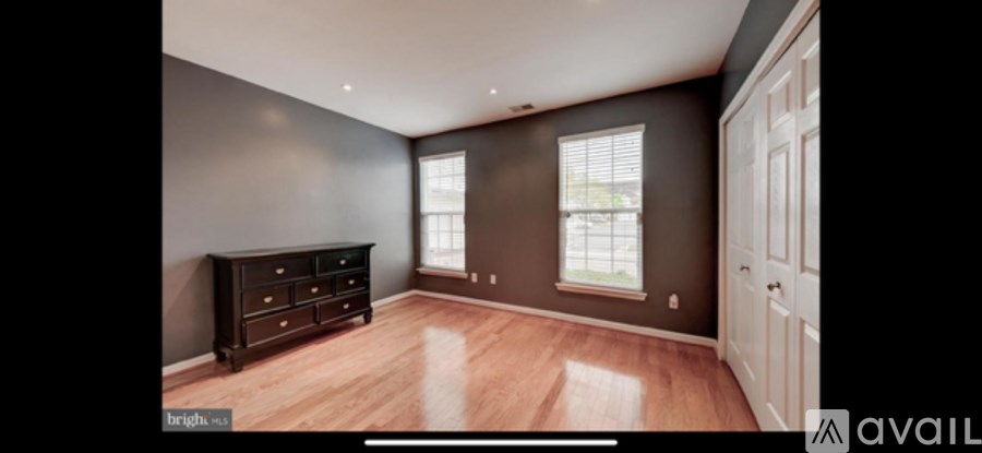 A spacious room with a wooden floor and a large window.