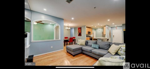 A living room with a grey couch and a blue wall.