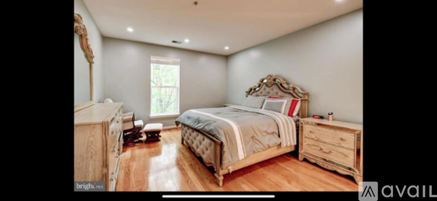 A bedroom with a large bed, wooden dresser, and a window.
