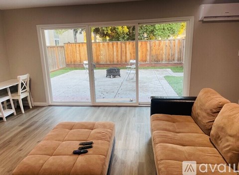 A living room with a couch, a chair, and a table with a remote control on it.