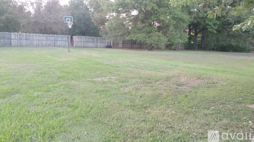 A basketball court is surrounded by a fence and trees.