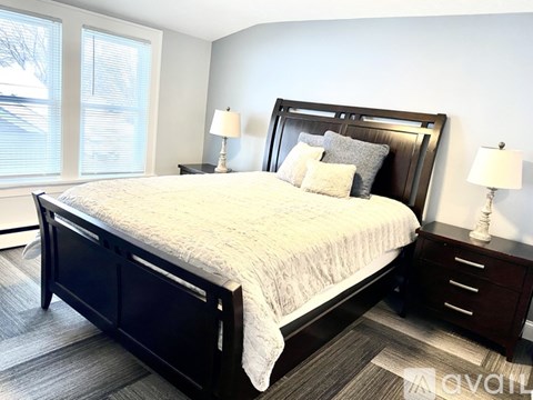 A bedroom with a large bed and two lamps.
