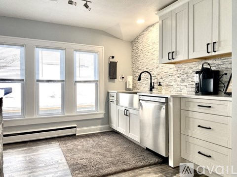 A kitchen with white cabinets and a stone backsplash.