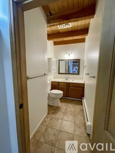 A bathroom with a toilet, sink, and mirror.