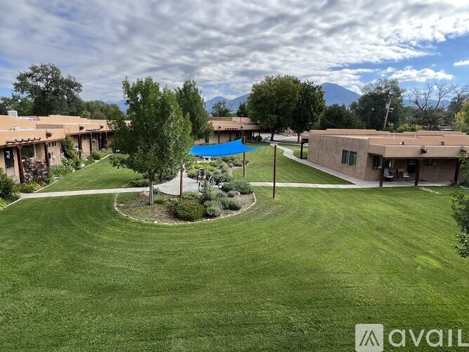 A grassy area with a blue umbrella and a building in the background.