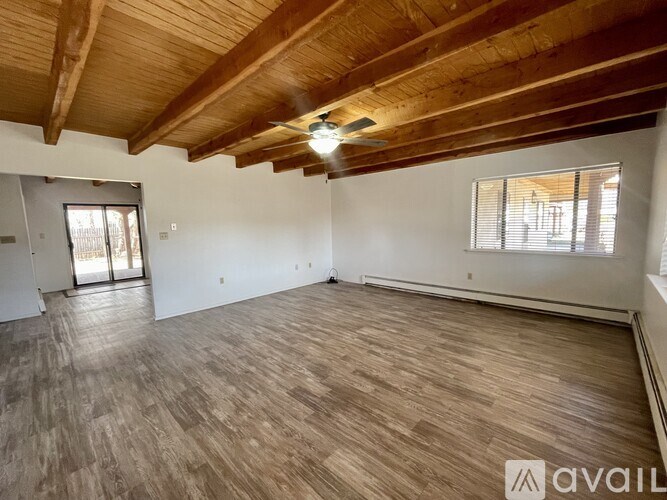 A spacious room with wooden flooring and a high ceiling.