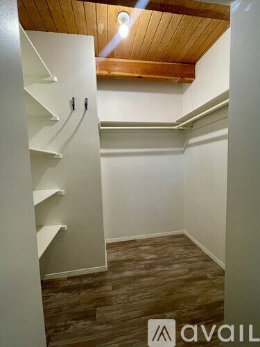 A wooden ceiling with a white wall and a white shelving unit.