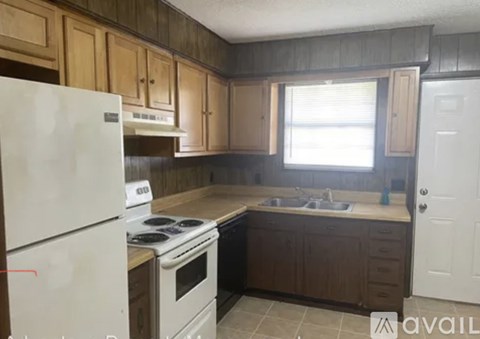 A kitchen with a white refrigerator, a white stove, and wooden cabinets.