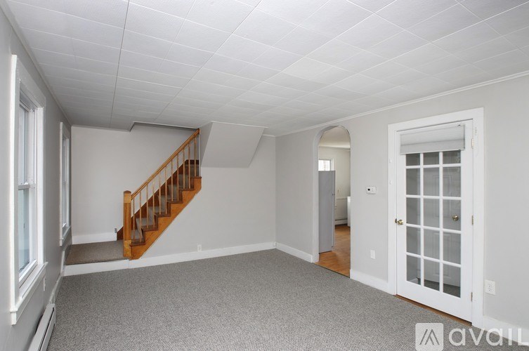 A spacious room with a staircase and a door leading to another room.