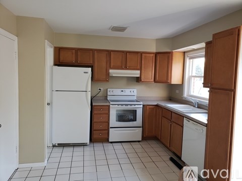 A kitchen with white appliances and brown cabinets.
