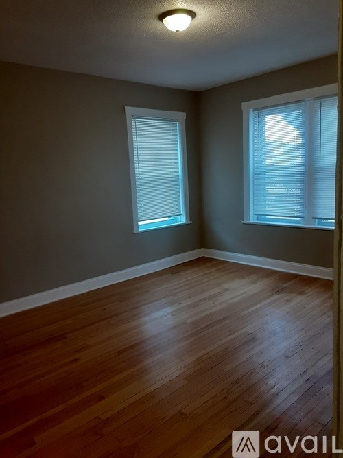 A room with wooden floors and two windows.