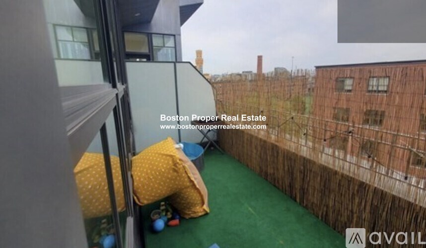 A balcony with a green carpet and a view of a brick building.