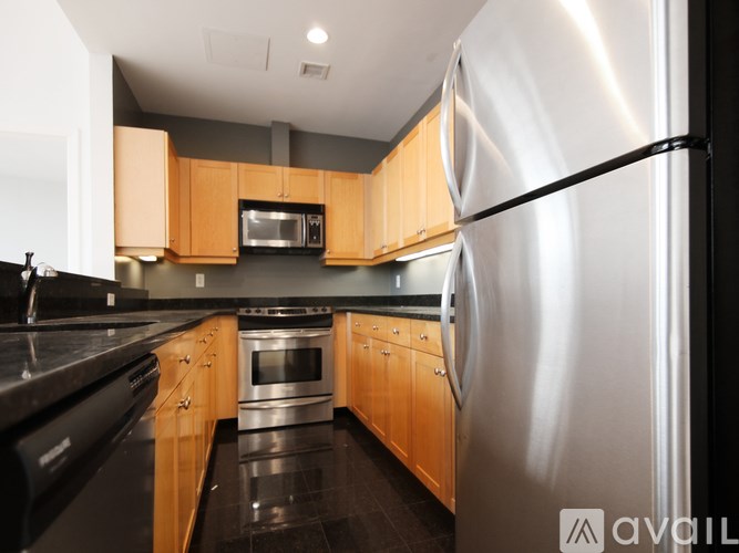 A modern kitchen with wooden cabinets and a stainless steel refrigerator.