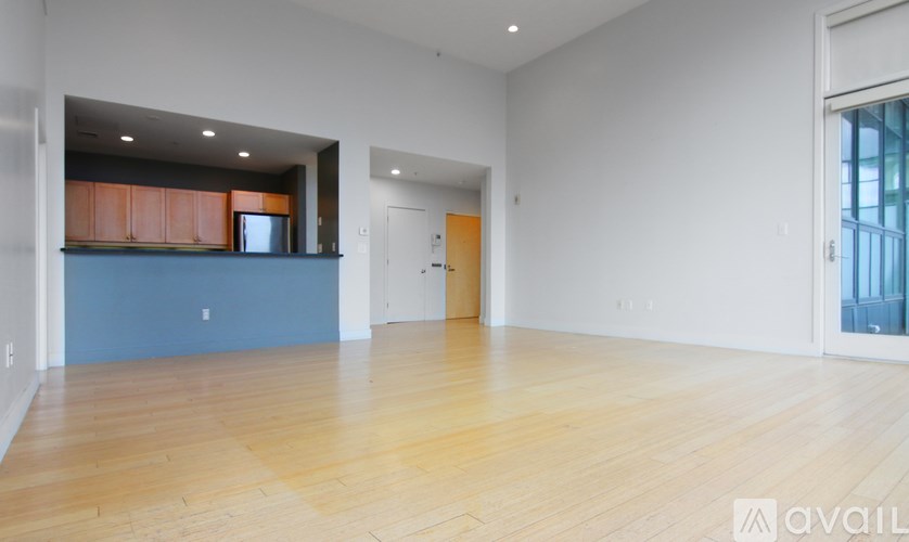 A spacious room with wooden flooring and white walls.
