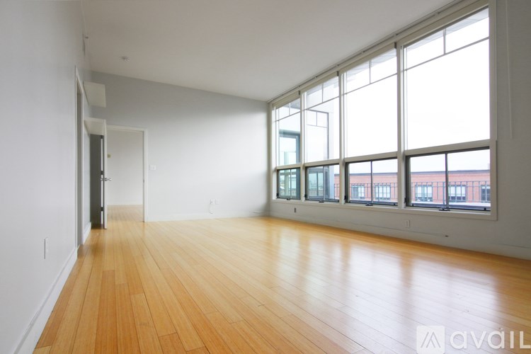 A large empty room with wooden floors and large windows.