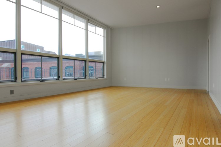 Empty room with wooden floors and large windows.