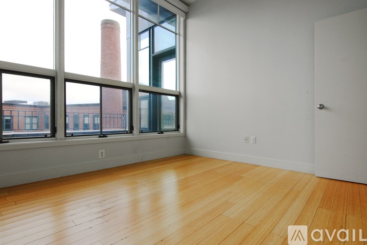 A room with wooden floors and a large window overlooking a brick building.