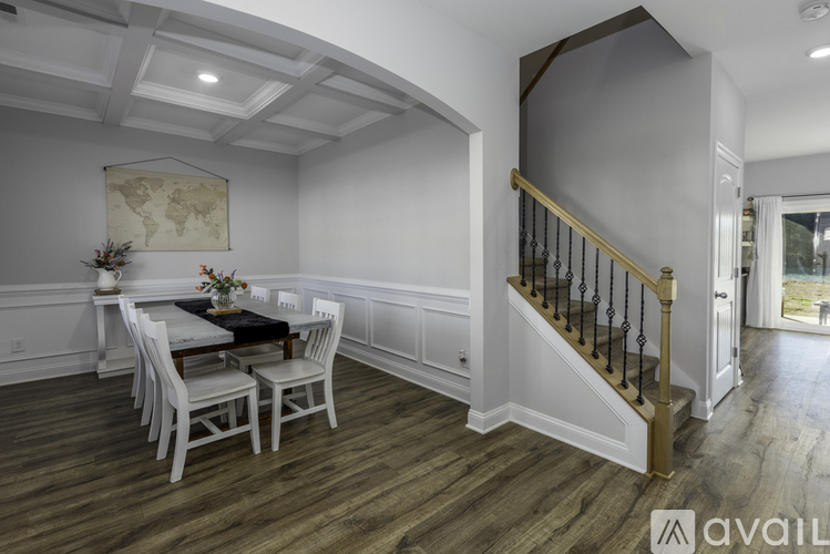 A dining room with a wooden floor and a white table with chairs.