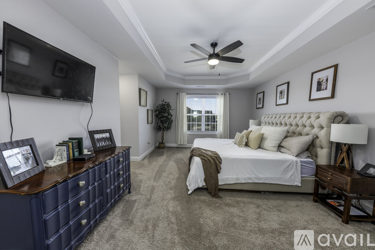 A bedroom with a large bed, a dresser, and a ceiling fan.