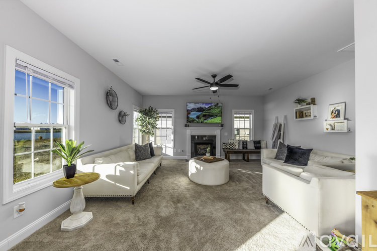 A living room with a white couch, a yellow side table, and a flat-screen TV mounted on the wall.