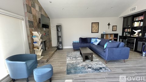 A living room with a blue couch and a fireplace.