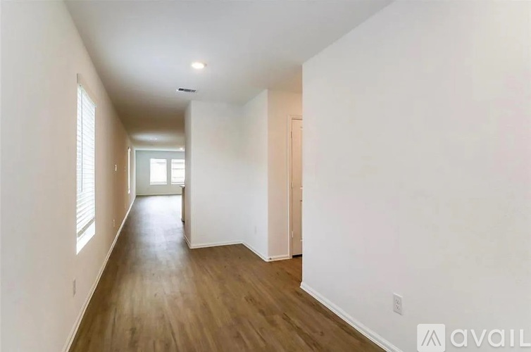 A long hallway with wood floors and white walls.