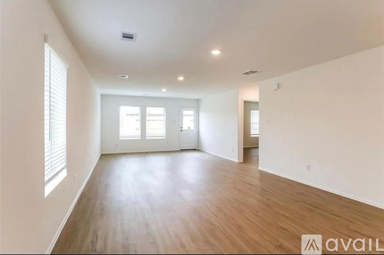 A spacious room with wooden floors and white walls.