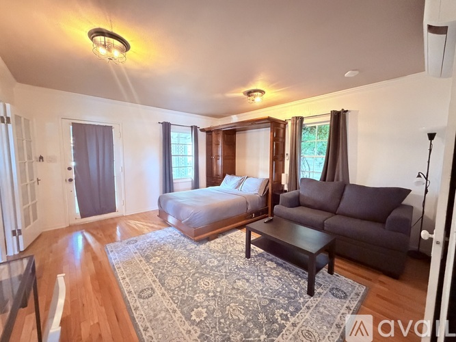 A black couch with a white pillow and a white blanket on it.