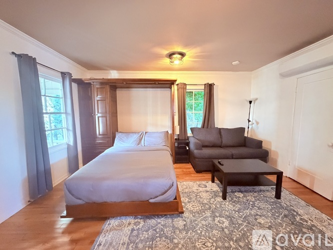 A living room with a television and a rug on the floor.