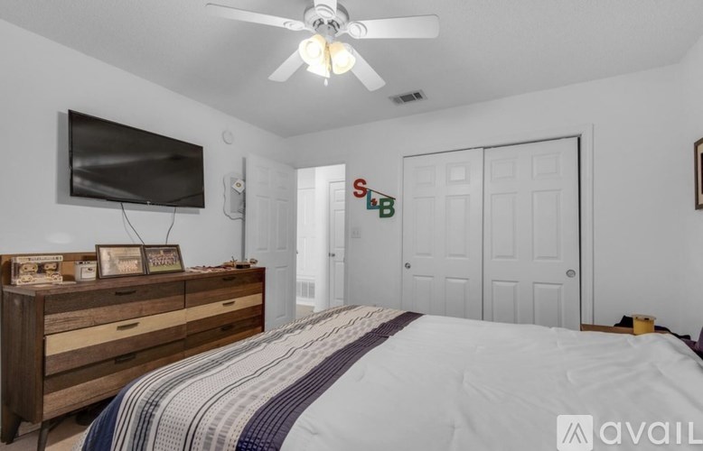A bedroom with a bed, dresser, and a ceiling fan.