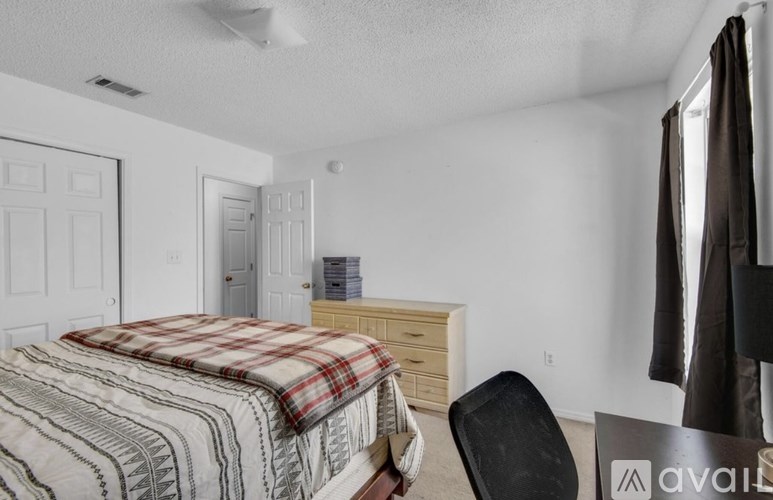 A bedroom with a bed, chair, and a dresser.