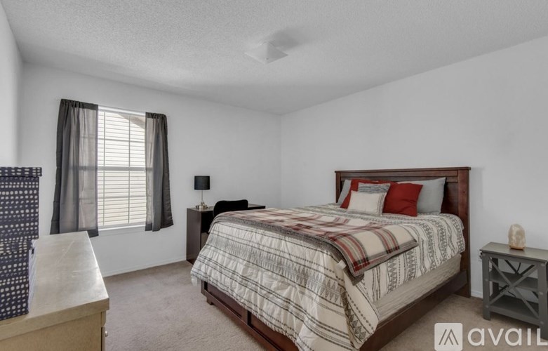 A bedroom with a bed, nightstand, and window.